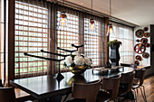 Glass pendant lights above dining table with hydrangea in copper vase
