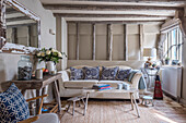 Rustikales Wohnzimmer mit Holzbalken und blau-weißen Kissen auf hellem Sofa