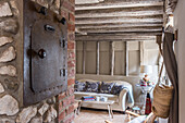Rustikales Wohnzimmer mit altem Ofen, Holzbalkendecke und Sofa