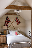 Sloped ceiling bedroom with Union Jack decor and wooden furniture