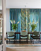 Dining room with mint green chairs, floral arrangements and patterned curtains