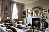 Classic living room with light-coloured upholstered furniture and a roaring fireplace