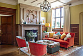 Traditionally furnished living room with red sofa, two armchairs and fireplace