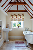 Country-style attic bathroom with freestanding bathtub and wooden beams