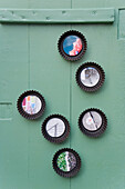 Photos in upcycled baking dishes hanging on a green wooden wall