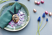 Plate, cloth napkin, chocolate eggs, grape hyacinths and Easter bunny made of eggshell