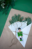 Geschenkpapier verziert mit Tannenzweigen, Zierdeckchen und kleiner Nussknackerfigur