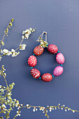 Blossoming twigs and DIY wreath made of red spotted Easter eggs