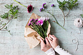 Hands of woman wrapping bunch of flowers