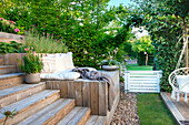 Wooden terrace with cushions surrounded by lush greenery in the garden