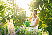 Young woman watering flowers in springtime garden