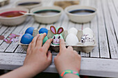Close-up of girl decorating Easter egg on garden table