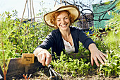 Glückliche junge Frau mit Strohhut Urban Gardening