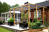 Black lacquered, mobile raised beds on wooden terrace with pergola