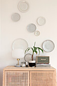 Wall decoration with plates above a rattan dresser with retro radio