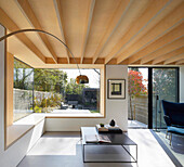 Minimalistisches, lichtdurchflutetes Wohnzimmer mit Holzdecke, Blick in den Garten