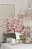 Branches of cherry blossom in vase on table set for afternoon coffee