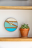 DIY wall clock made of cork coaster next to potted succulent