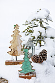 Little fir trees made of wood, lantern and pine cones in snowy landscape