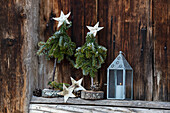 DIY miniature trees and lantern in front of wooden wall