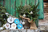 Holzstämme mit Weihnachtsmotiven und Winterstrauß mit Juteband im Blecheimer