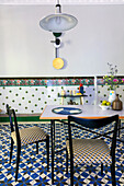 Dining table with Italian chairs in front of tiled wall with border