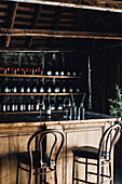 Rustic bar with wooden counter, shelves with wine bottles