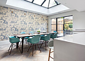 Dining area with turquoise-coloured chairs and wallpaper with Toile de Jouy pattern