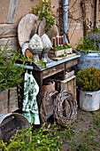 Gartentisch mit Pinienzapfen, Adventskerzen, Kränzen, Zweigen und Zinkgefäßen