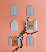 Small arched window with shutters in light blue on pink wall