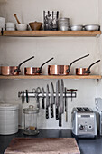 Antique copper pots with carbon steel knives on a magnetic rack
