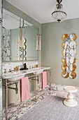 Doppelwaschbecken und Spiegel im Bad mit Marmorboden, im Hintergrund Designer Wandteller an der Wand