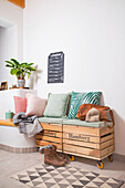 Bench made from wooden crates with cushions and decorative plant