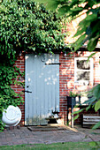 Alte, hellblaue Holztür mit abblätternder Farbe an einer Ziegelwand
