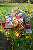 Autumnal table setting in the garden with pumpkin decoration and bouquet of flowers