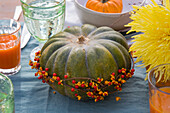 Pumpkin with berry wreath as table decoration, glasses