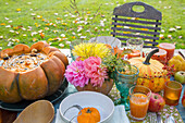 Autumnal garden table with pumpkin soup and flower arrangement