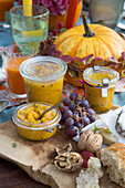 Pumpkin chutney in jars with grapes and nuts on a wooden board