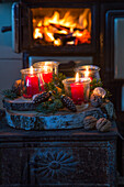 Windlichter mit roten Kerzen auf weihnachtlich dekorierter Baumscheibe