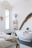 Palmwedel hinter freistehender Badewanne im Schlafzimmer