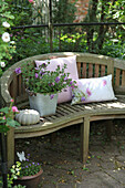 Garden bench with cushions and miniature petunias in pots