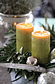 Weihnachtliches Gesteck mit grünen Kerzen, Silberkugeln und Kranz auf Olivenzweigen