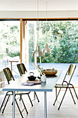 Dining table with folding chairs and pendant lights above and view of the terrace