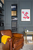 Brown leather armchair in corner of room with grey walls and mouldings