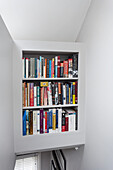 Wall of bookshelves above narrow staircase