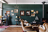 Wohnbereich mit Vintage-Sofas, Kaminofen, Teppichen und gerahmten Bildern an dunkler Wand