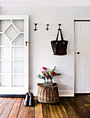 A tote hangs in the mud room above posies from the garden and a fisherman’s basket