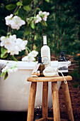 Wooden stool with bath additive in front of outdoor bathtub - gift idea for wellness
