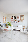 Two white tables as room divider to the living room with picture gallery
