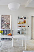 White dining table with fruit bowl in front of string shelf with vintage deco